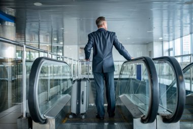 Man with the baggage going down the moving staircase