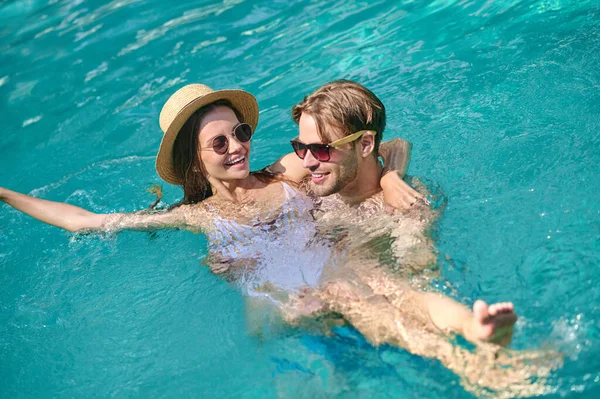 Young couple swimming in a pool and feeling excited — Stock Photo, Image