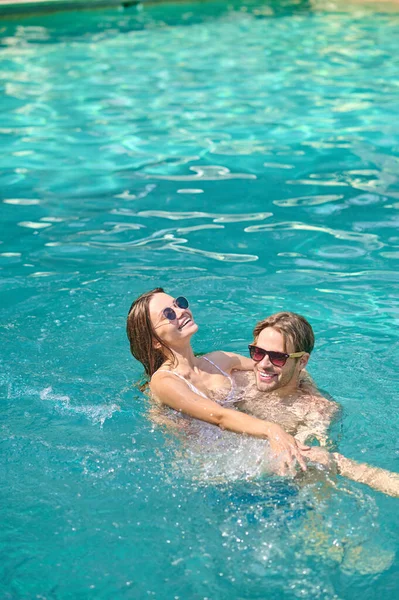 Young couple swimming in a pool and feeling excited — Stock Photo, Image