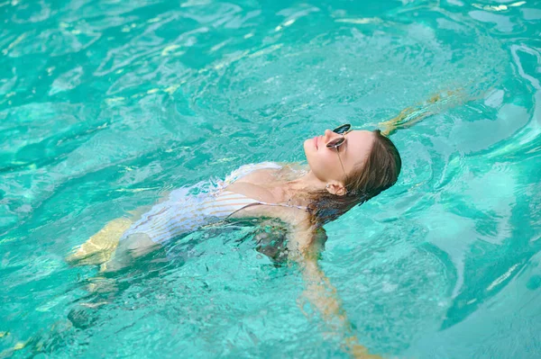 Young woman laying on water and looking relaxed — Photo