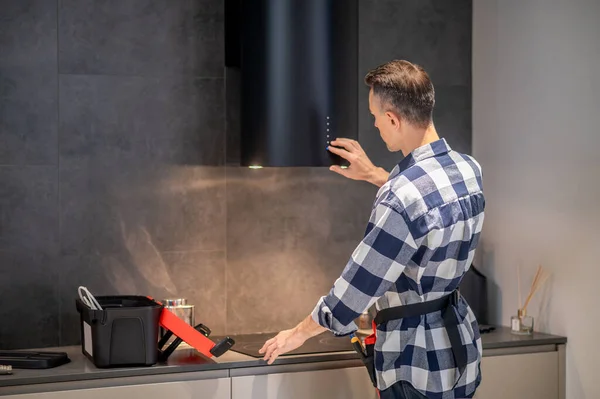 Back view of man touching kitchen appliance hanging on wall — 스톡 사진