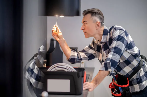 Profile of man touching lamp on kitchen hood — 图库照片
