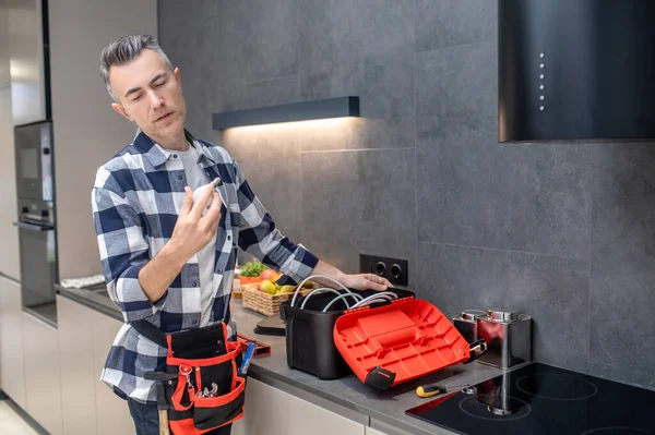 Man with tools looking closely at lamp in hand — Stock Photo, Image