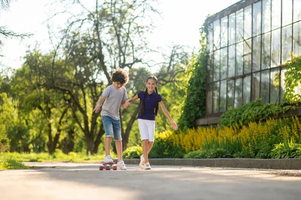 Cheerful girl teaching a boy to skateboard — Stockfoto