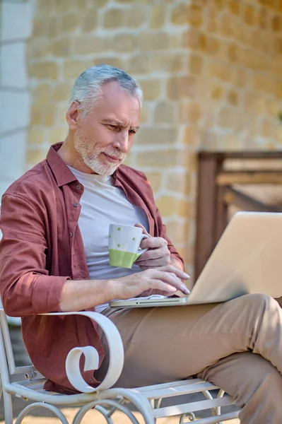 A man in burgundy shirt with a laptop in hands —  Fotos de Stock