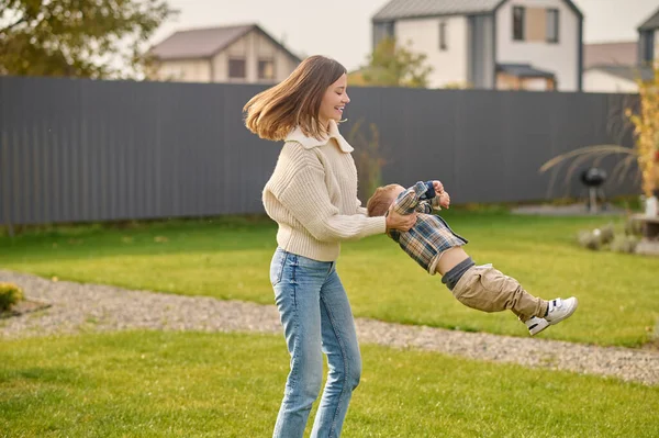 Woman sideways to camera circling her baby on lawn — Foto de Stock