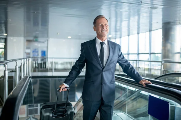 Smiling handsome middle-aged guy stepping off the escalator — Stockfoto