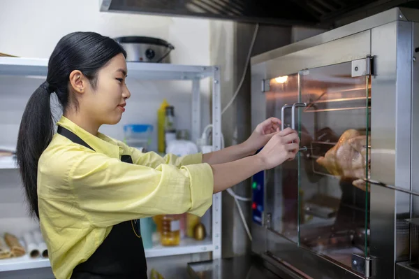 Joven mujer asiática trabajando en la cocina y regulando la temperatura de los hornos — Foto de Stock