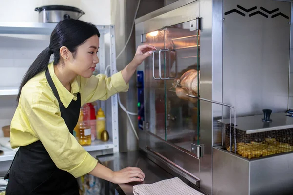 Young asian woman working in the kitchen and regulating ovens temperature — Foto de Stock