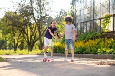 Concentrated boy teaching his friend to skateboard