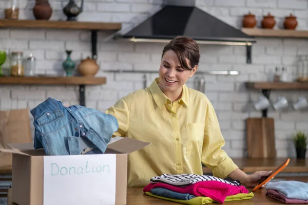 Joyful vlogger packing clothes for donation before the camera — Foto Stock