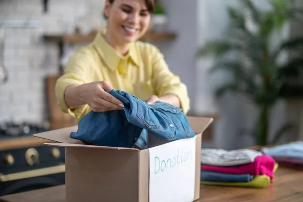 Focused contented female packing clothes for donation — Foto de Stock