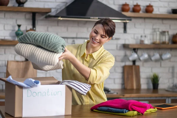 Chica caucásica alegre preparando ropa para la donación — Foto de Stock
