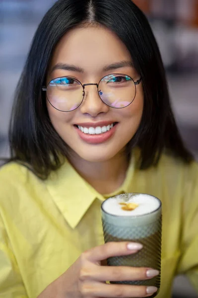 Χαριτωμένη Ασιάτισσα με γυαλιά στο λάπτοπ να πίνει καφέ. — Φωτογραφία Αρχείου