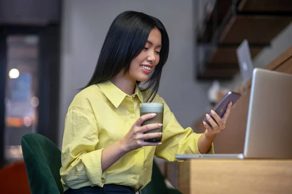 Pretty young asian woman in yellow shirt working on a laptop — Stock Fotó