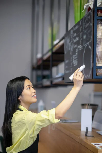 Asian young woman writing menu on a board in a cafe — Fotografia de Stock