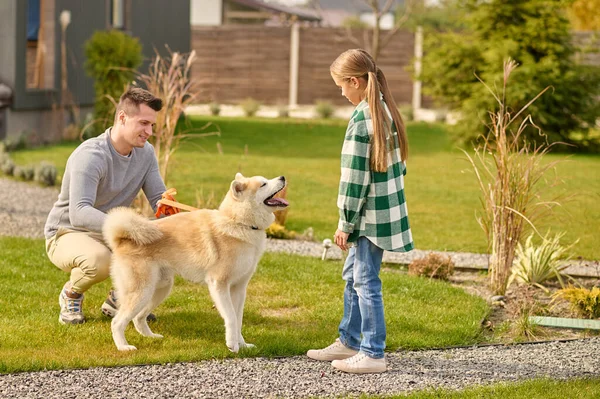 Man crouching near dog and girl looking outdoors — стоковое фото