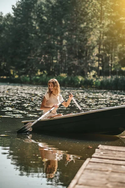 A woman sitting in a boat and oaring — Stockfoto