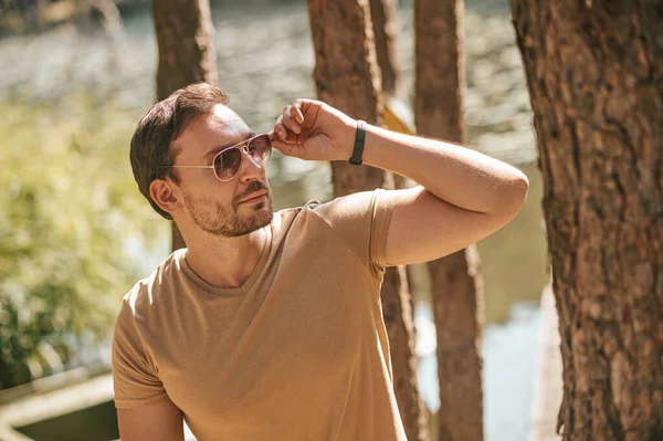 A young man in sunglasses in the forest near the river — Stockfoto