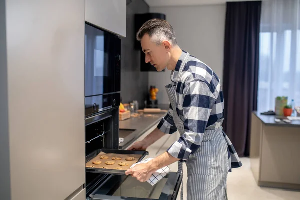 Man putting baking sheet in oven — Fotografia de Stock