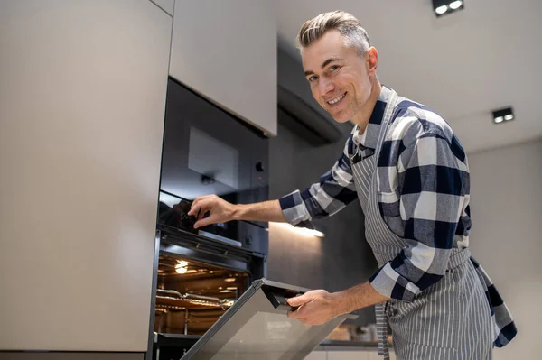 Man turning toggle switch of oven looking at camera — Stok fotoğraf