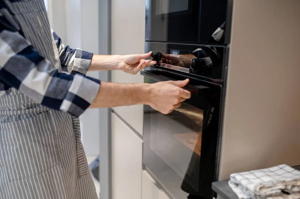 Male hands touching control panel and oven handle — Stok fotoğraf