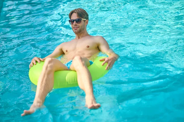 Jeune homme avec un tube jaune dans une piscine — Photo