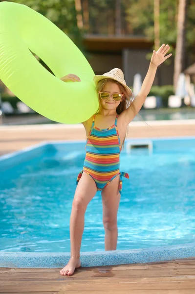 Menina bonito com um tubo amarelo na piscina — Fotografia de Stock