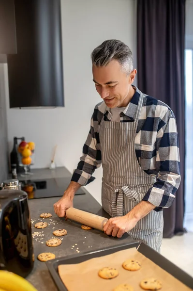 Чоловік формує печиво з прокатним штифтом, дивлячись на стіл — стокове фото