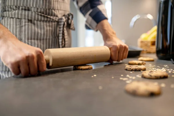 Руки человека нажимают скалку на сырое печенье — стоковое фото