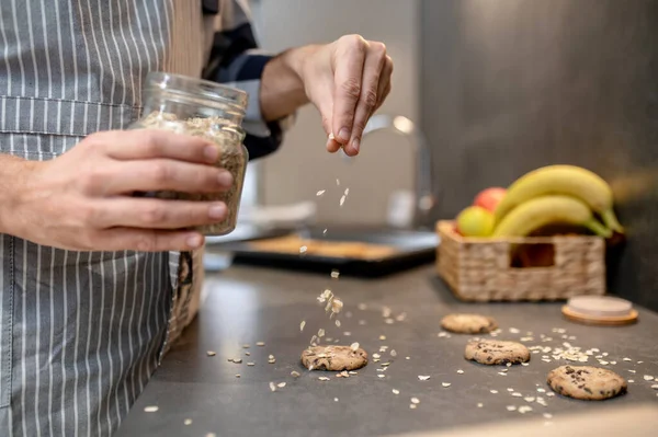 Mannelijke hand besprenkelende rauwe koekjes met amandelschijfjes — Stockfoto