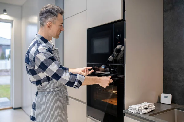 Perfil do homem tocando interruptor de alternância e porta do forno — Fotografia de Stock