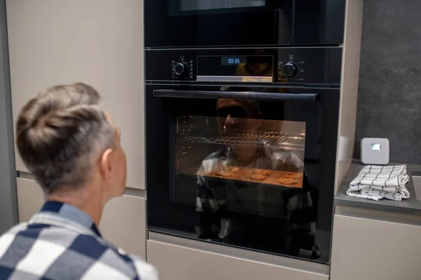 Back view of crouched man looking at working oven — Stock Photo, Image