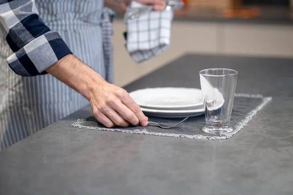 Мужская рука кладет вилку на салфетку возле тарелки — стоковое фото