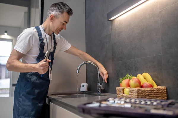 Man openen kraan kijken naar jet van water — Stockfoto