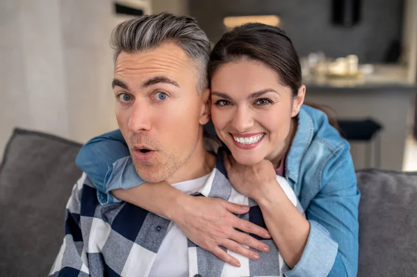 Frau umarmt fröhlichen Mann und blickt in Kamera — Stockfoto