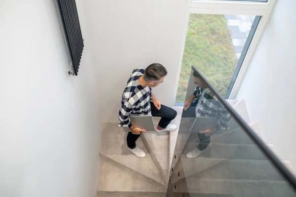 Ovanifrån av man med bärbar dator på trappor inomhus — Stockfoto