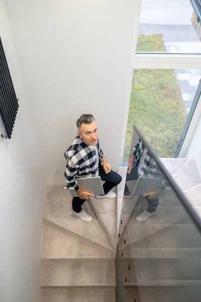 Man med bärbar dator klättra trappor tittar på kameran — Stockfoto