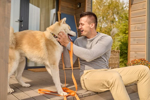 Profil de l'homme assis sur le porche touchant son chien — Photo