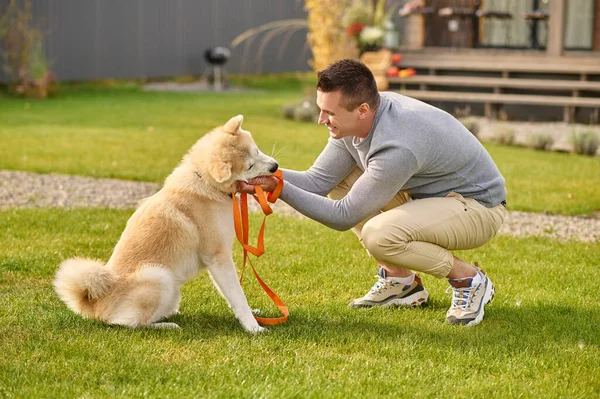 Sideways to camera man crouching touching dog with leash — Stock Photo, Image