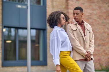 Kadın kamera önünde kararsız adamın omzuna dokunuyor.