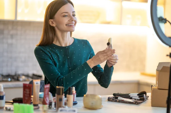 Joven cosmetólogo sonriente explicando los secretos del buen maquillaje — Foto de Stock