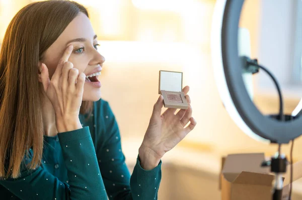 Joven sonriente mujer shpowing nuevo sombras de ojos a onine audiencia — Foto de Stock