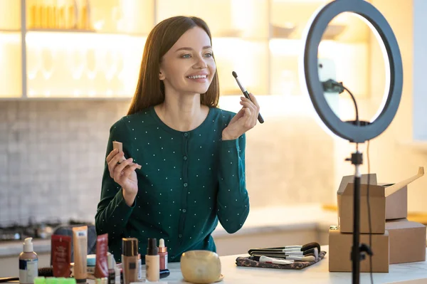 Mujer joven en vestido verde que muestra consejos de maquillaje en línea — Foto de Stock