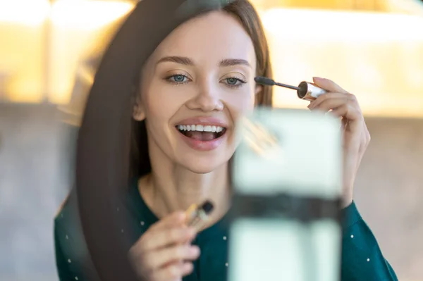 Young beautiful woman demonstrating new mascara and looking amused — Stock Photo, Image