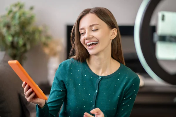Весела молода жінка в зеленій сорочці перед фотоапаратом робить онлайн майстерню — стокове фото