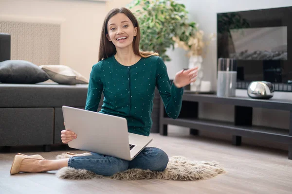 Mujer joven de pelo largo sentada en el suelo con una computadora portátil — Foto de Stock