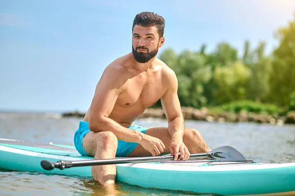 Well-built young man in blue shorts kayaking — Stock Photo, Image