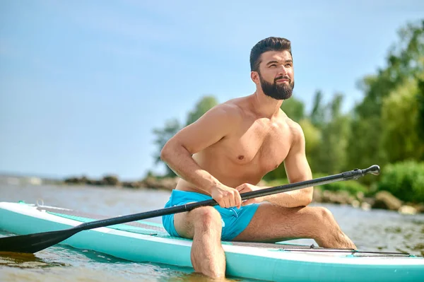 Well-built young man in blue shorts kayaking — Stock Photo, Image