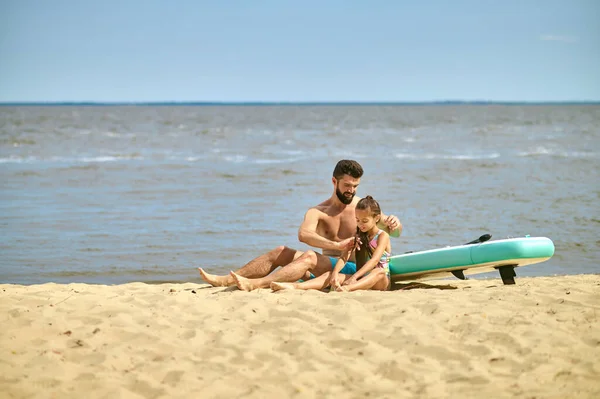 Темноволосый мужчина проводит время со своим ребенком на пляже — стоковое фото